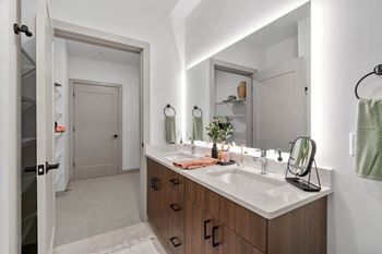 A bathroom with a sink, mirror, and wooden cabinets.